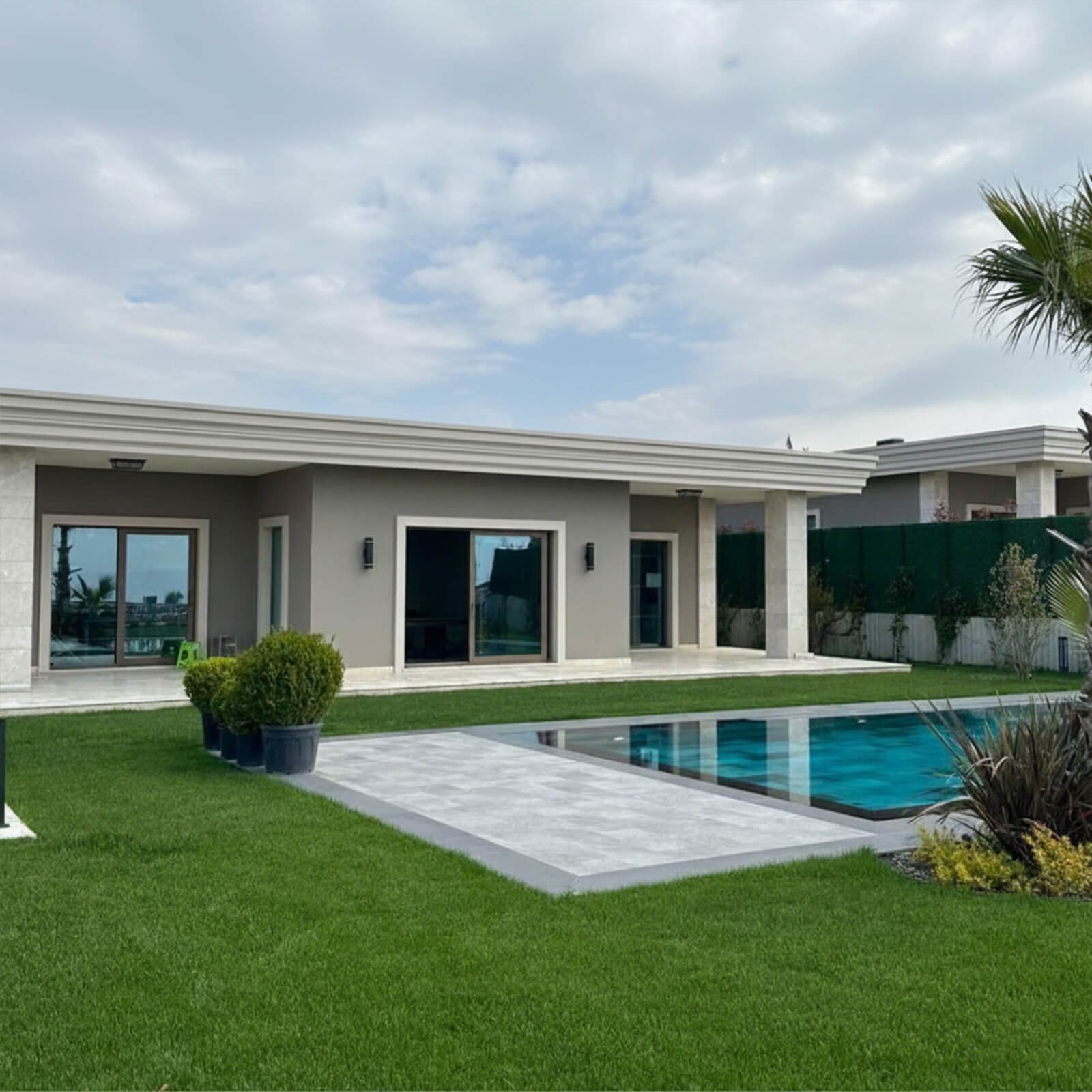 Tek katlı modern villa mimarisi, yüzme havuzu ve geniş bahçe peyzaj tasarımı.